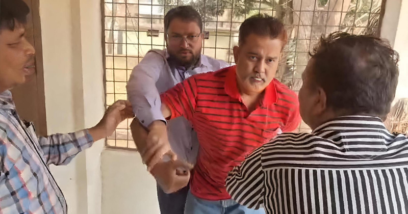 প্রধান শিক্ষককে পেছন থেকে ধরে রাখছেন হিসাবরক্ষণ কর্মকর্তা | ছবি : খোলা কাগজ